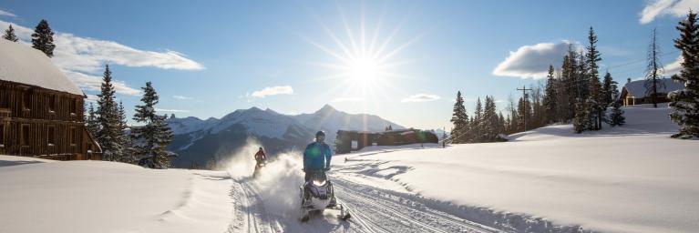 Line of snowmobilers on a snowmobile track during a sunny day. 