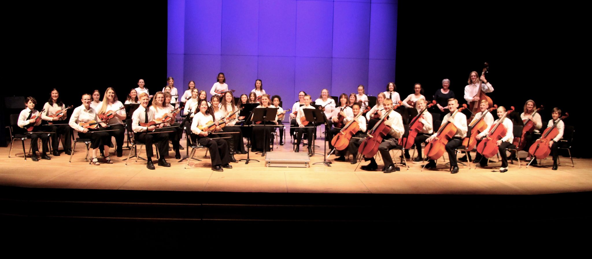 Group photo of the Valley Youth orchestra on stage holding instruments