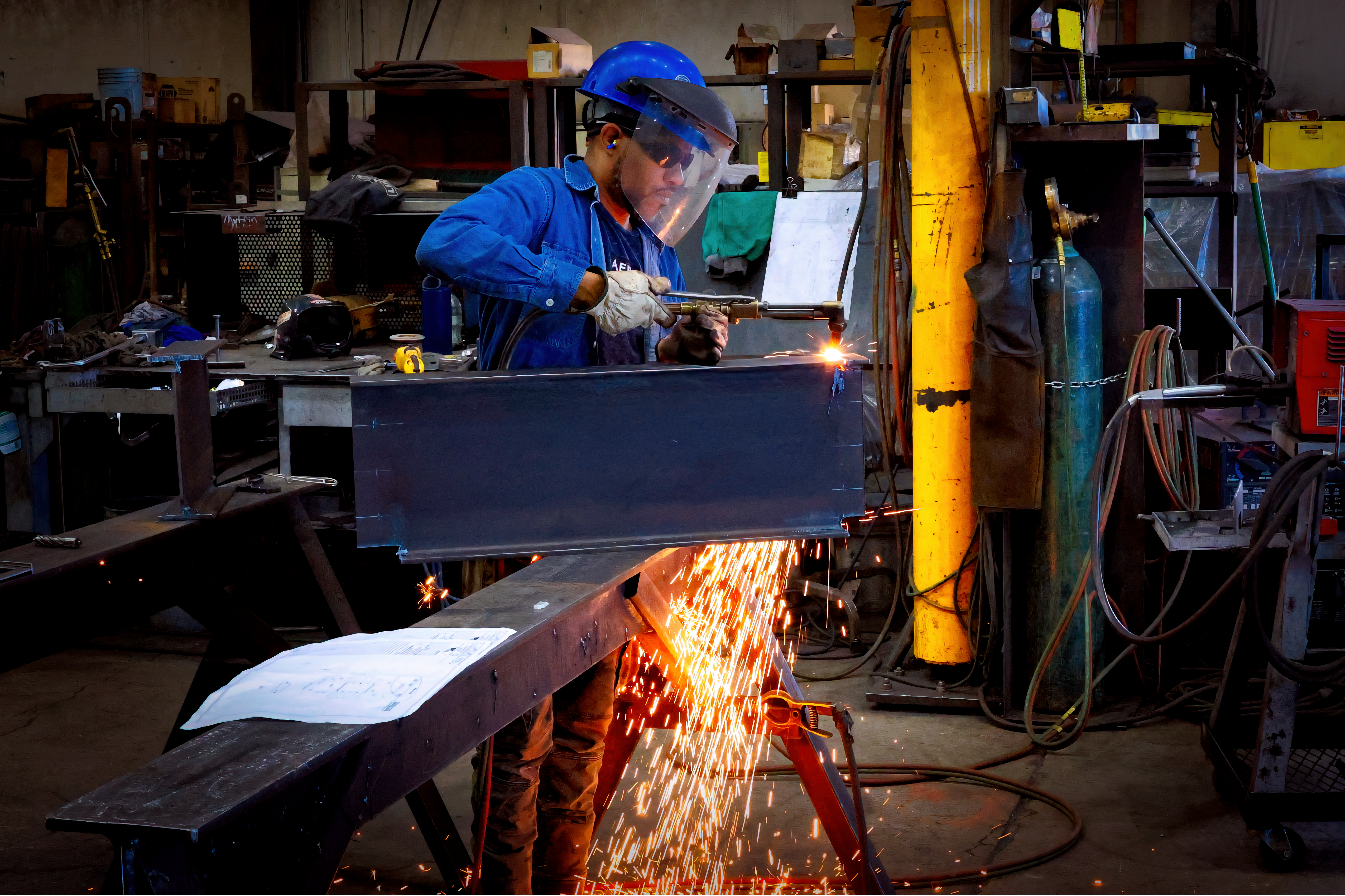 A Rocky Mountain Steel employee actively welding a large piece of steel