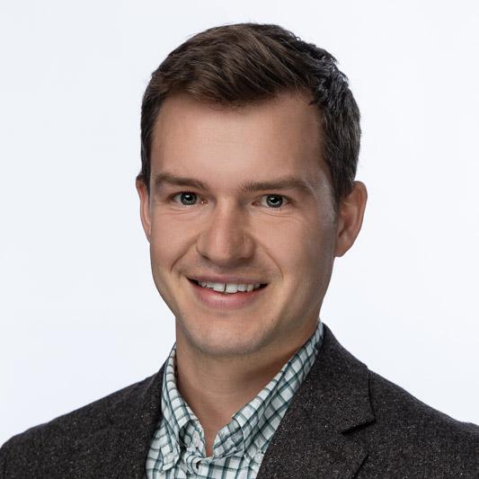 Jack Tiebout, man with brown hair wearing a heather grey wool jacket and green and white plaid button-down 