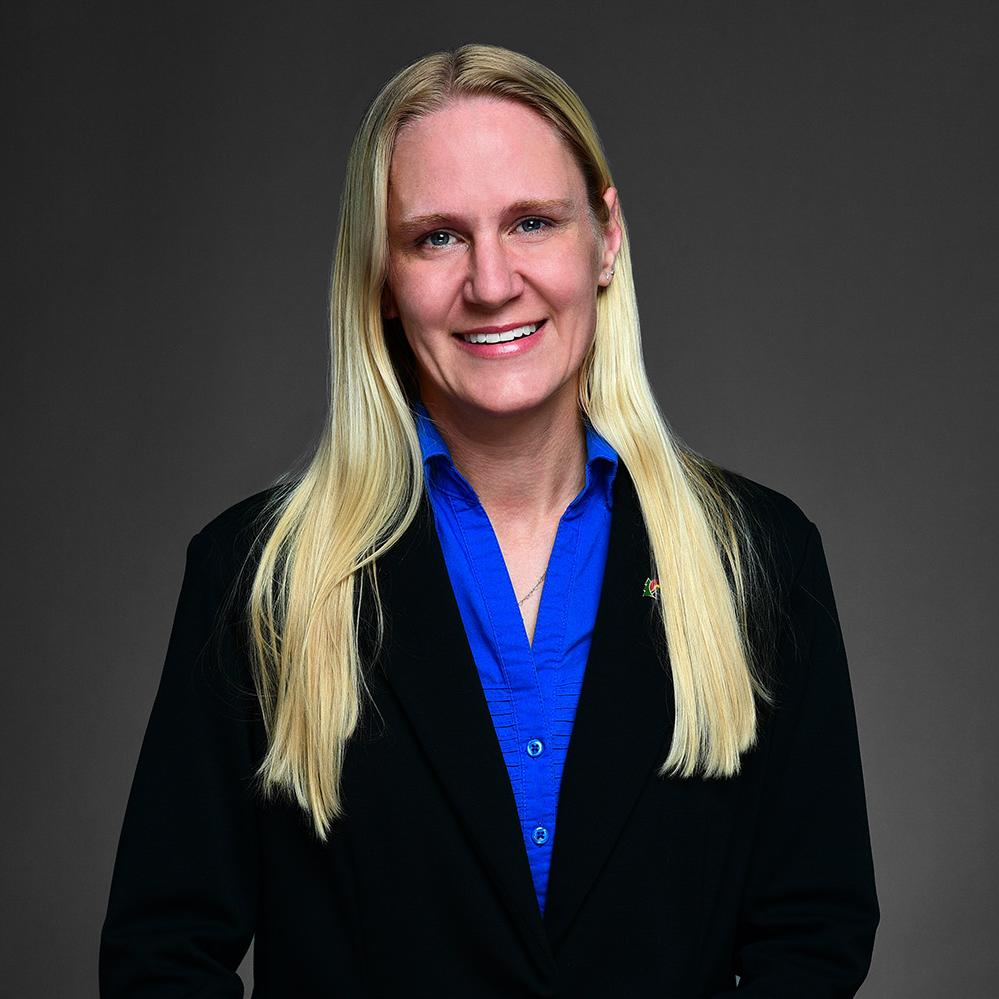 Headshot of Crystal Walsh. She is wearing a black business suit with a blue collard shirt. She has blonde long hair and is wearing a state of Colorado on the right side of her suit. 
