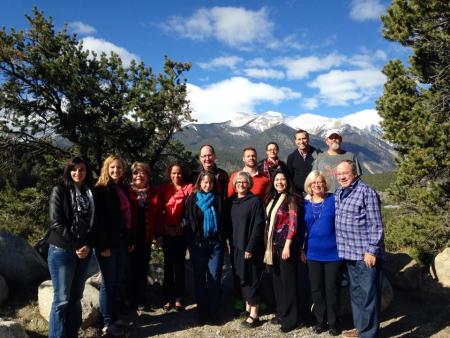 14 change leaders pose in a line in front of a mountain view framed by trees