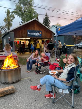 group of people sitting around a fire, representing the company town hall outdoor co.