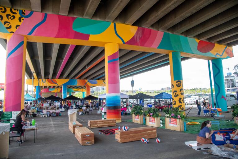 Volunteers set up a night market under the Colfax Viaduct and beneath a brightly colored mural