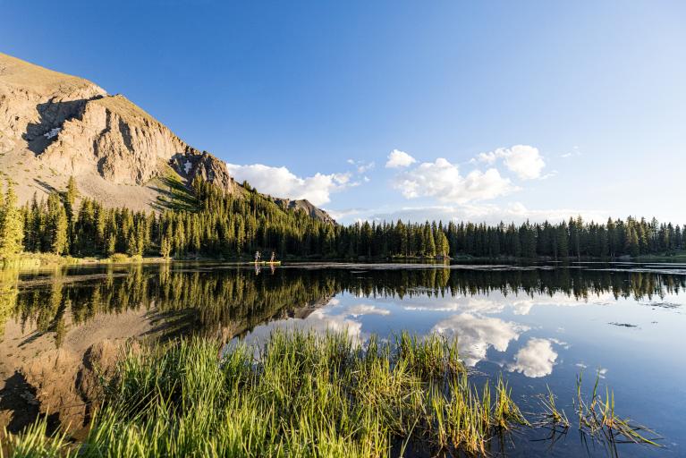 Two people paddleboarding on a lake surrounded by mountains