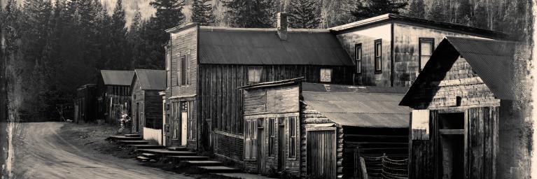 Vintage photo of old western buildings in the middle of mountains