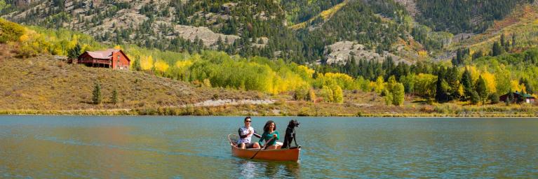 Couple in canoe with dog and fall background on Marble lake. 