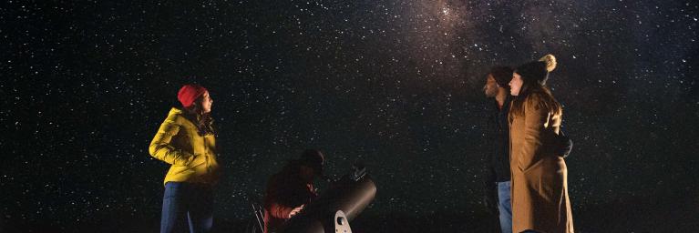 People stargazing under the milky way with a telescope. 