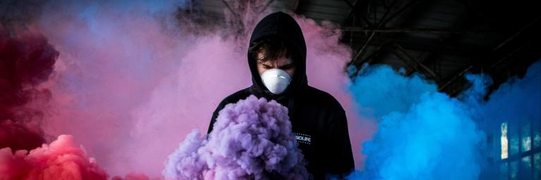 man wearing mask in colored smoke