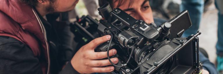 closeup of two men filming behind professional video camera