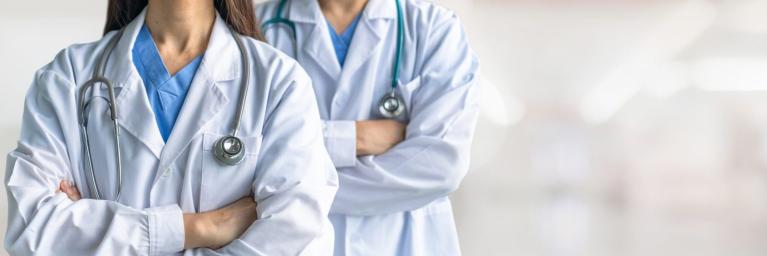 Two doctors stand side by side with arms crossed