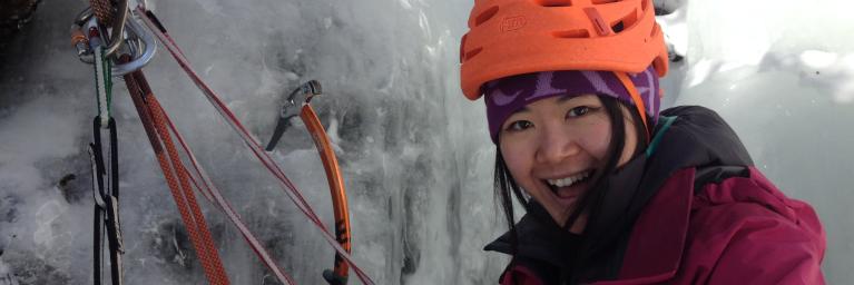 girl in helmet at anchor while ice climbing