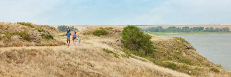 A family of four walks along a path next to a lake in Logan County