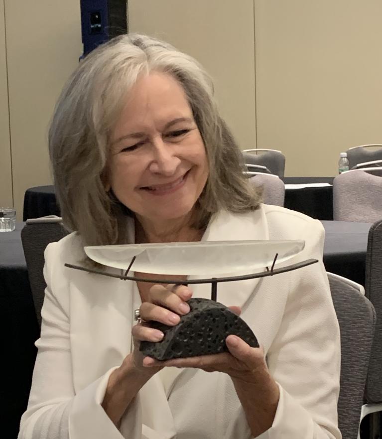 CCI Director Margaret Hunt holding the Luminary Award with a smile