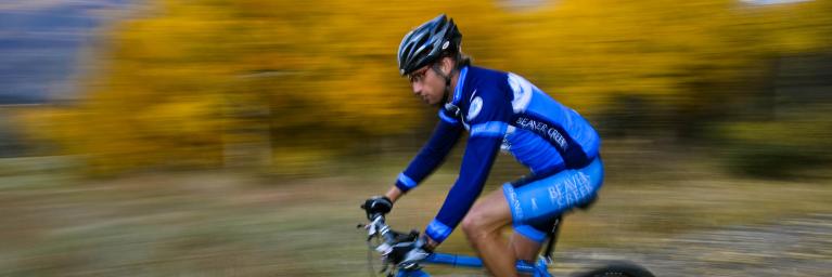 A mountain biker riding through yellow fall leaves