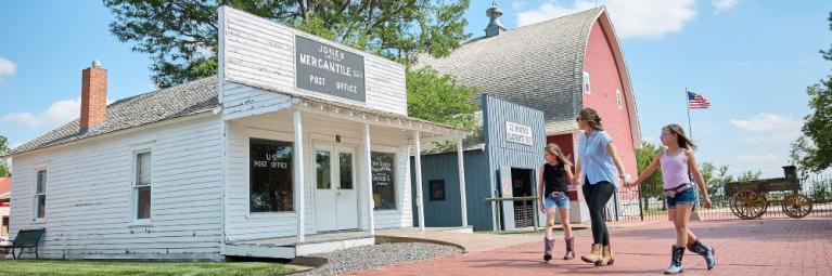 A family of three walks through a historic western village scape.