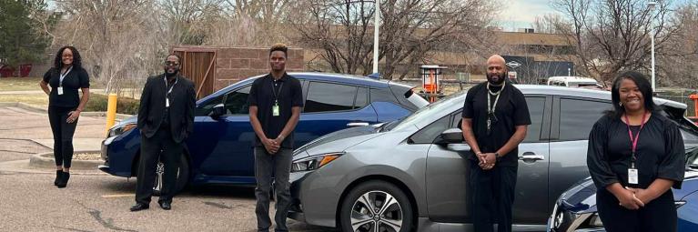 5 high demand delivery employees standing in front of delivery cars