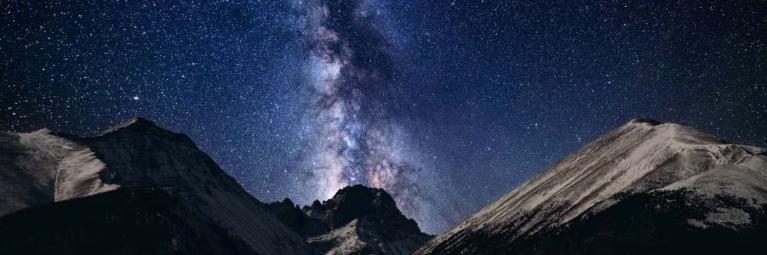 The Milky Way in the night sky between two mountain peaks over Saguache County.