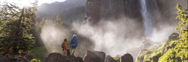 Two hikers standing at the base of a waterfall