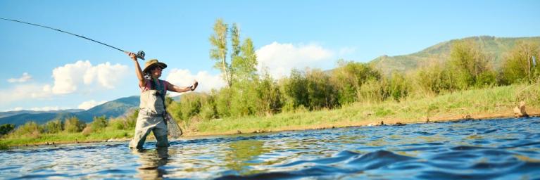 An angler casts their fishing rod into a river