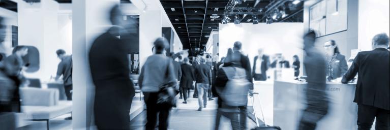 Black and white photo of blurred people walking through a trade show