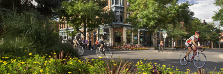 Bicyclists pass through old town Fort Collins on a summer day.