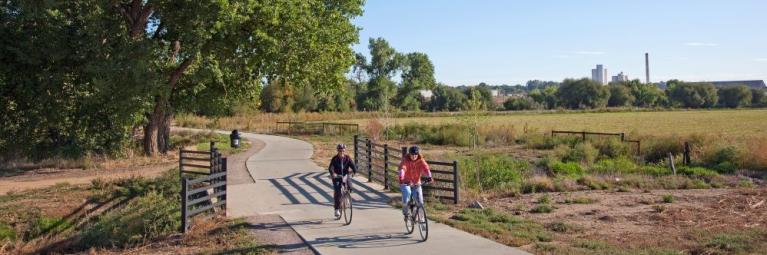 A pair of bicyclists crosses a bridge on a bike path in Longmont.