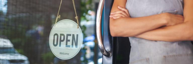 Business owner stands in front of her shop to welcome customers