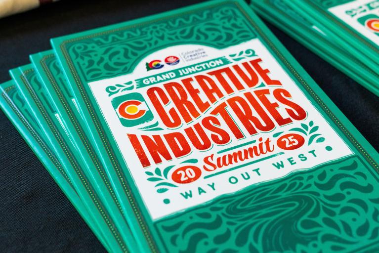 a stack of 2025 CCI Summit programs that are colorfully designed 