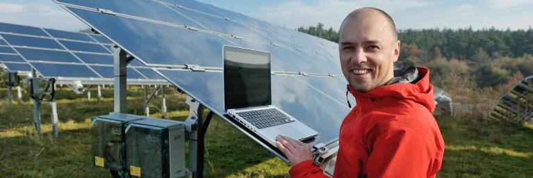 engineer using laptop at solar panels plant field