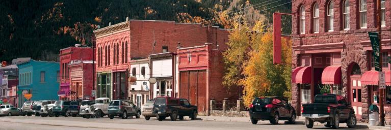 cars in front of colorful old building in the town of Silverton, Colorado with snow-covered mountains
