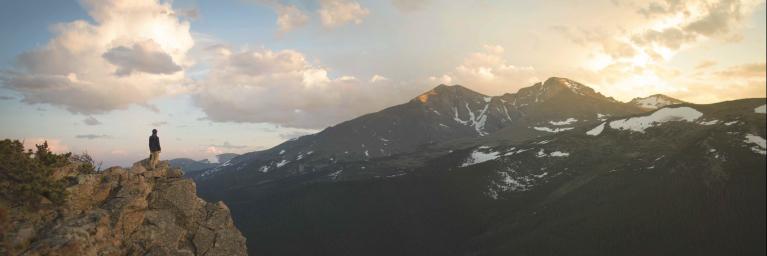 woman overlooking Colorado mountains at sunset