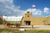 covered wagon in front of pueblo building at Bent's Old Fort