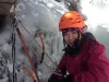 girl in helmet at anchor while ice climbing