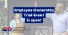 Two people high five in front of shop with text saying employee ownership trial grant is open