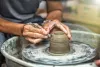 Artist works at a pottery wheel to carve a vase